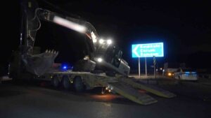 Deprem bölgesine giden tırın taşıdığı iş makinesi yola devrildi